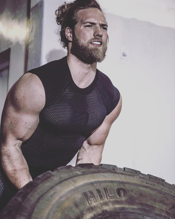 Ripped and muscular Lasse Matberg lifting a heavy tire.