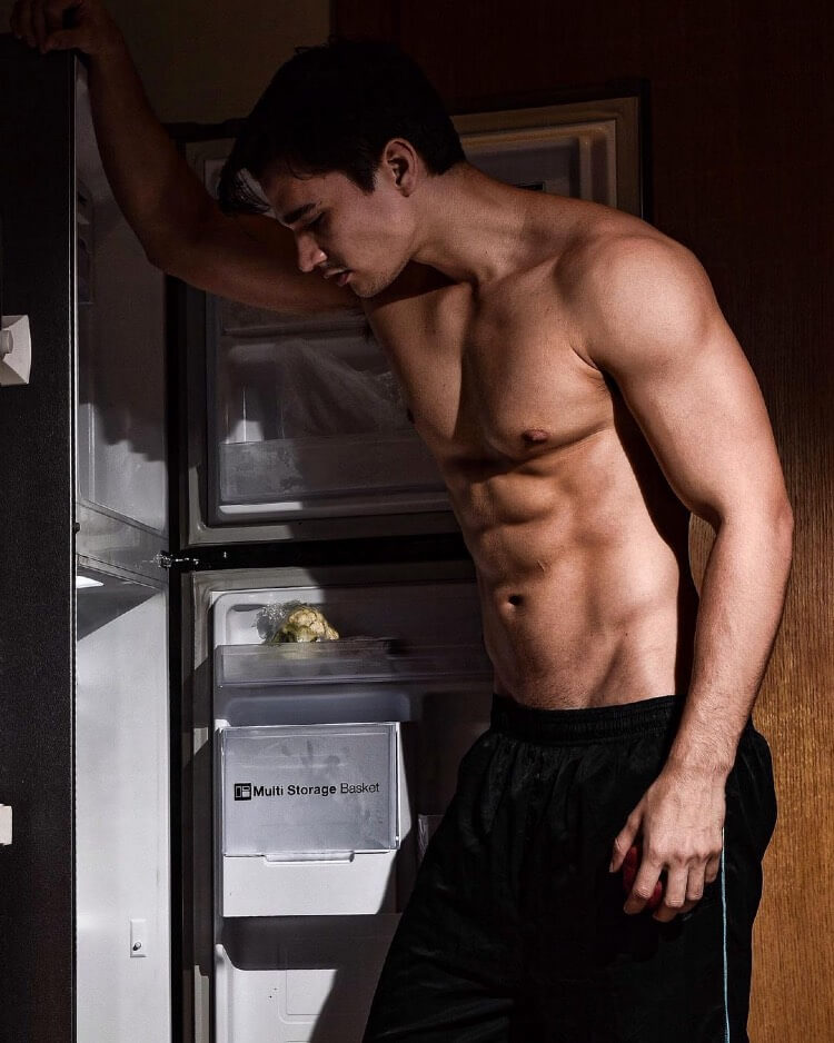 Hans Weiser posing shirtless in front of a fridge, looking lean and muscular.